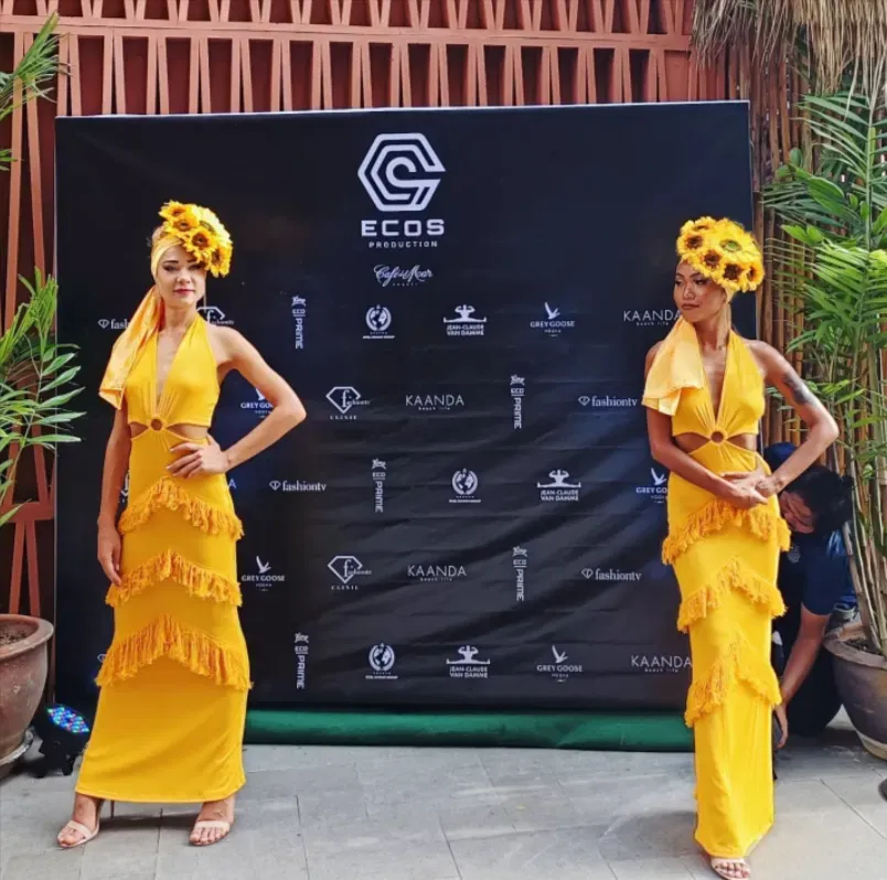 Models in yellow fringed dresses at the ECOS Production event backdrop